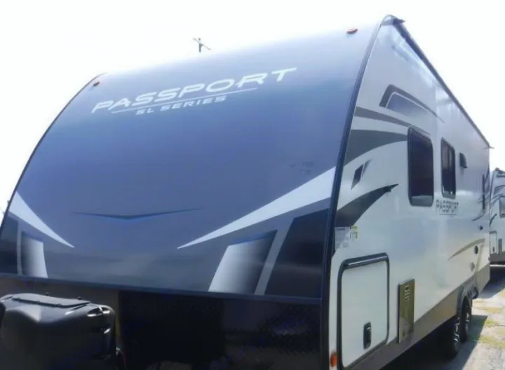 This front and side view shows a white and grey Passport SL Series travel trailer, ready for your next RV rental adventure.. Keystone RV Passport SL 2021