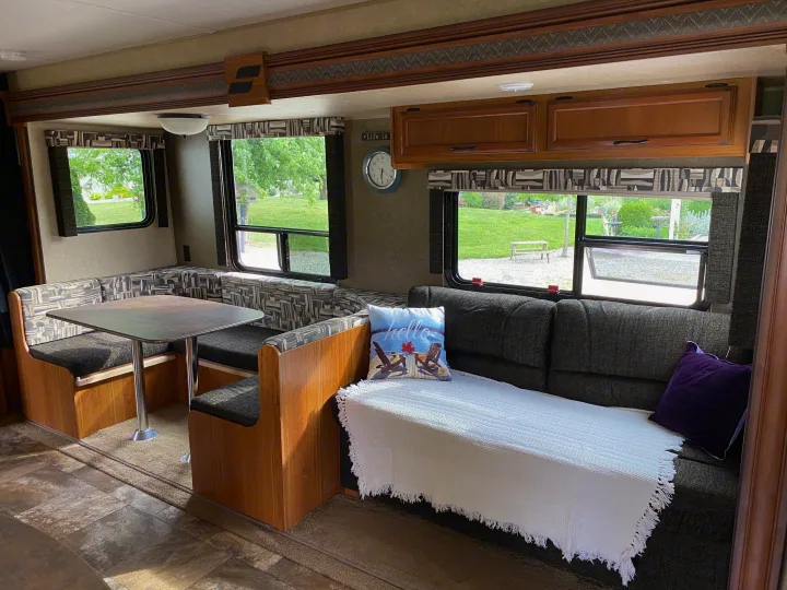 Spacious RV rental interior with U-shaped dinette, sofa, and large windows showing a lush green outdoor scenery.. Starcraft Ar-One MAXX 2016
