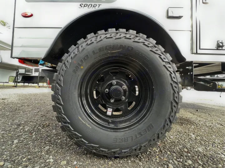 Close-up of a rugged Westlake Mud Legend tire on an RV rental, showcasing its deep treads and black rim.. Sunset Park RV SunRay 2023