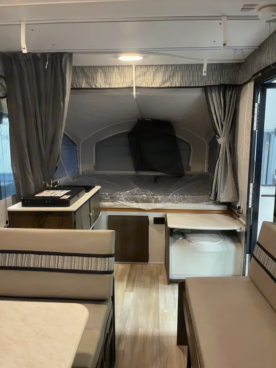 Well-appointed RV rental interior featuring a kitchenette, dining area, and comfortable sleeping space with a portable toilet.. Coachmen Clipper Sport 108ST 2022