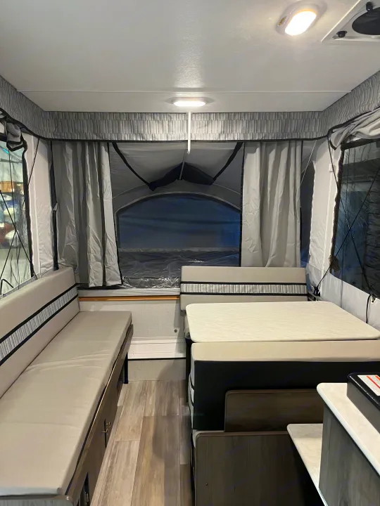 Inside a modern RV rental pop-up camper, showing a cozy dinette and convertible beds for a comfortable trip.. Coachmen Clipper Sport 108ST 2022