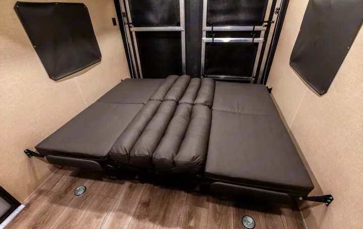 RV rental: Toy hauler interior with a grey convertible bed, offering flexible living and sleeping space.. Coachmen Catalina 2022