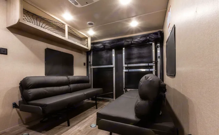 RV rental interior showing a versatile toy hauler garage with two fold-down sofas, overhead storage, and a rear ramp.. Coachmen Catalina 2022