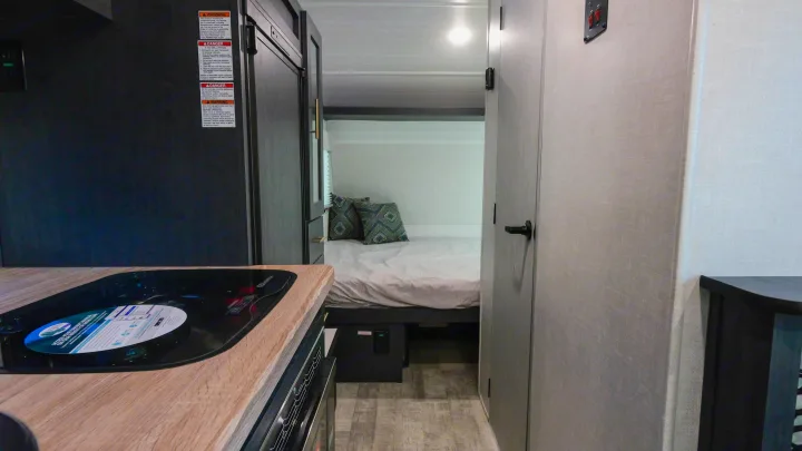 RV rental interior: A compact kitchen with a stovetop on the left, leading to the bedroom with a cozy bed.. Forest River R-Pod 190 2024