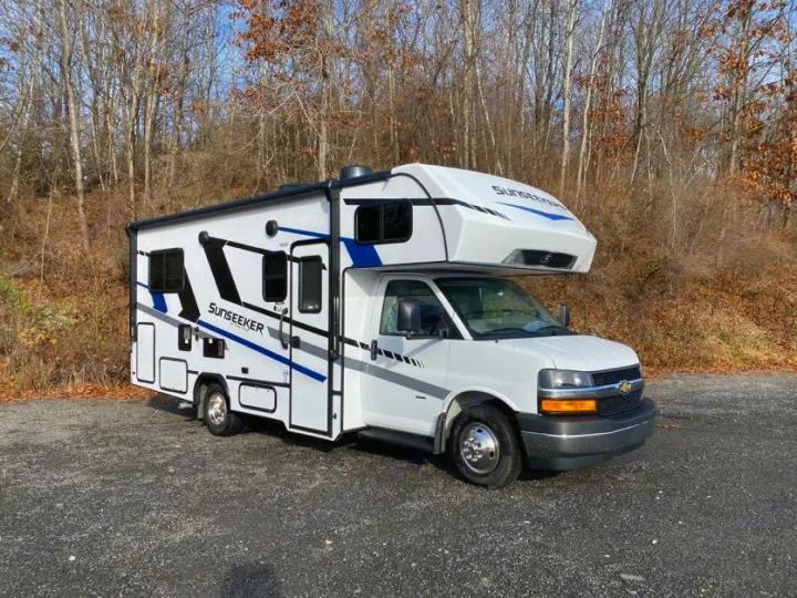 White Sunseeker rv rental: a Class C camper van parked on asphalt near bare trees, ready for your next road trip.. Forest River Sunseeker 2025