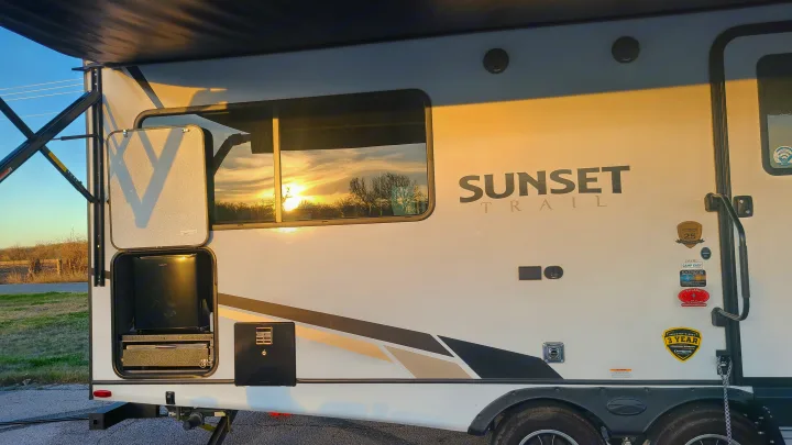 Enjoy an rv rental adventure! Sunset Trail travel trailer with an open outdoor kitchen, reflecting the sunset.. Crossroads RV Sunset Trail Super Lite 2022