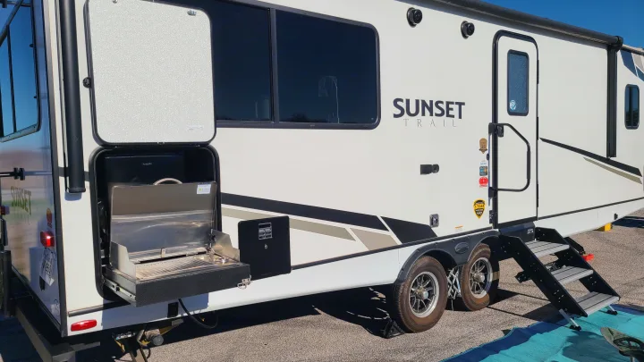 RV rental: A Sunset Trail travel trailer with its side hatch open, showcasing a pull-out outdoor kitchen and grill for easy camping.. Crossroads RV Sunset Trail Super Lite 2022