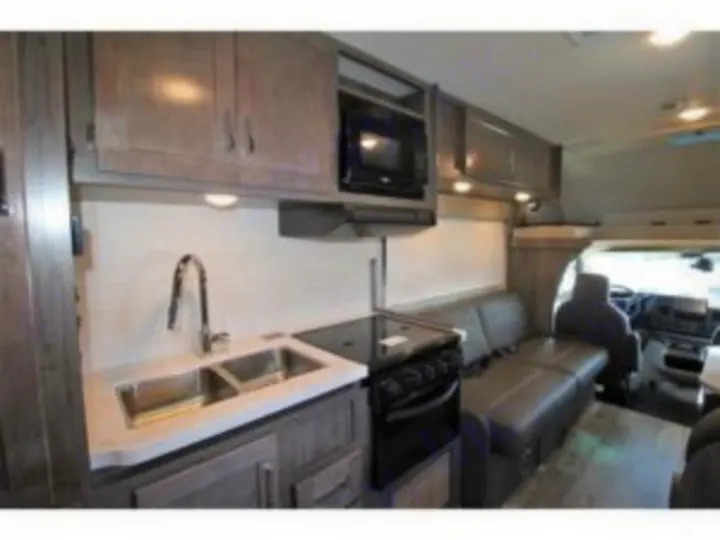Explore this RV rental's modern kitchen with a sink, stove, and microwave, plus comfortable dinette. Perfect for road trip adventures!. Winnebago Minnie Winnie 2024