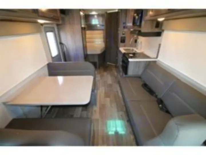 Comfortable RV rental interior: Features light gray sofas, a dinette table, and a compact kitchen, ideal for road trip living.. Winnebago Minnie Winnie 2024