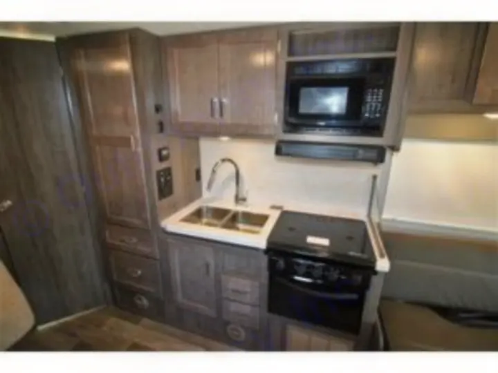 This RV rental features a modern kitchen with a microwave, sink, stovetop/oven, and ample storage.. Winnebago Minnie Winnie 2024
