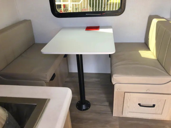 RV rental dinette with tan bench seats, white table, window, and drawer for a compact living space.. Forest River Rockwood Geo Pro 2024