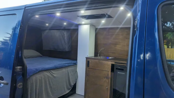 Inside a ready-to-go RV rental: This camper van features a comfy bed, functional kitchen, and built-in fridge.. Dodge Sprinter 2007