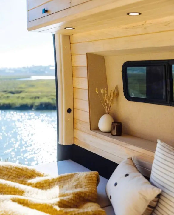This cozy RV rental offers a modern wood interior, soft seating, and a window view of a sparkling lake.. Vanspeed Mercedes Sprinter 2021