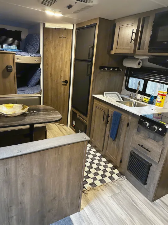 Inside a modern **rv rental** featuring a full kitchenette, dinette, and bunk beds for comfortable travel.. Heartland RVs Pioneer 2024