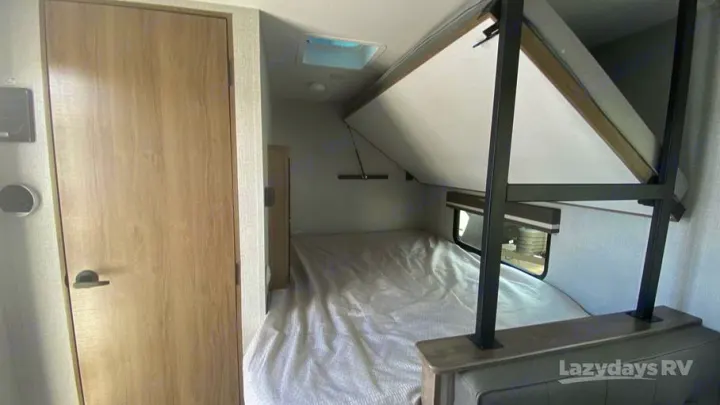 This rv rental interior shows a sleeping area with a lower bed and a folded-up upper bunk, maximizing space in this camper.. Grand Design 2023