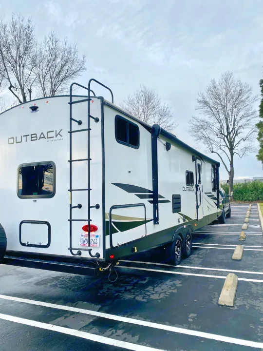 White Keystone Outback travel trailer parked in a lot, perfect for your next RV rental adventure.. Keystone RV Outback Ultra-Lite 2022