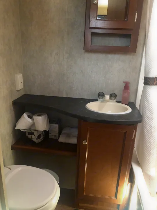 Efficient RV rental bathroom: toilet, sink, vanity with storage, & shower curtain. Ready for your adventure.. Keystone RV Bullet Ultra Lite 2015