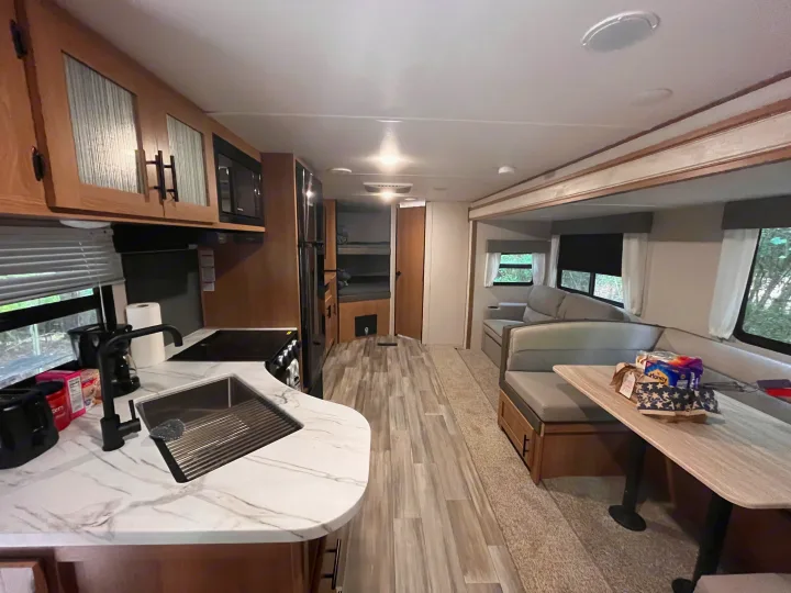 Bright RV rental interior featuring a modern kitchen, dining booth, and bunk beds for comfortable stays.. Forest River Prime Time Avenger 27 DBS 2023