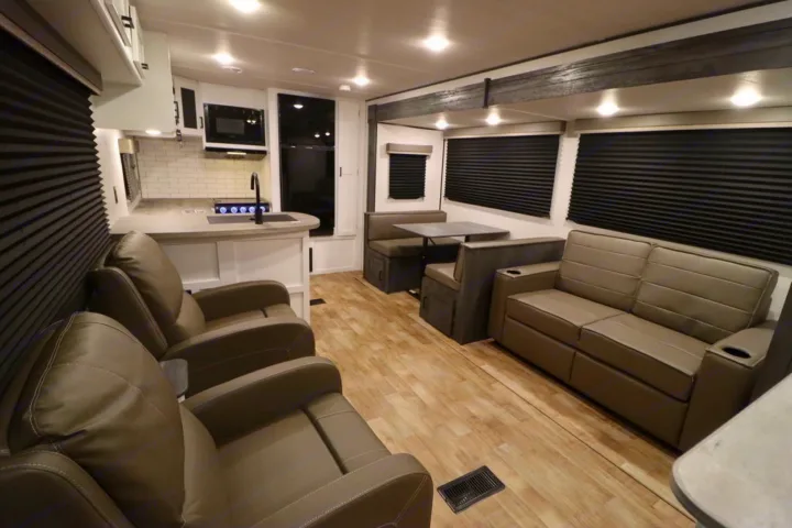 Spacious RV rental interior: modern kitchen, dining booth, comfy recliners, and sofa for your travels.. Keystone RV Hideout 2023