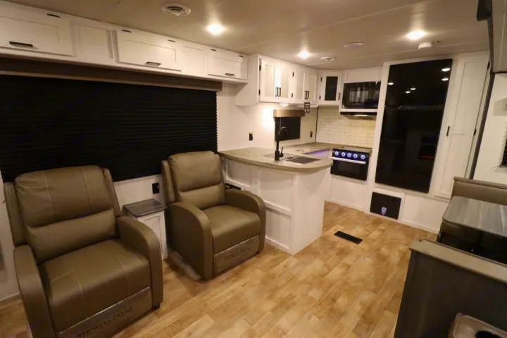 Spacious RV rental interior with a modern kitchen, comfortable recliners, and dinette area. Well-lit and functional.. Keystone RV Hideout 2023