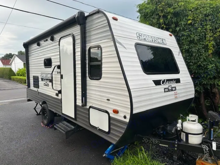 A white and grey Sportsmen Classic travel trailer for your next rv rental. Features an awning, steps, and propane.. KZ Classic 2022