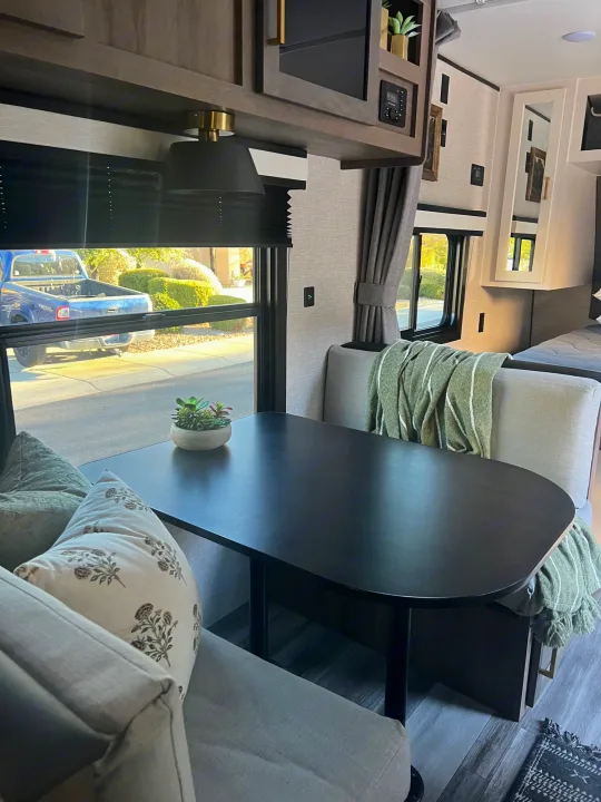Cozy RV rental dinette with a modern table, plush seating, and green blanket. Ideal for travel trailer getaways.. Jayco 224BHW 2024