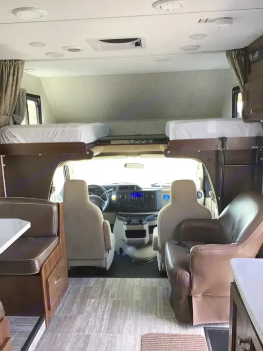 Modern rv rental interior showing cockpit, bunk beds, dinette, and armchair, ready for a comfortable road trip.. Forest River Forester 2020
