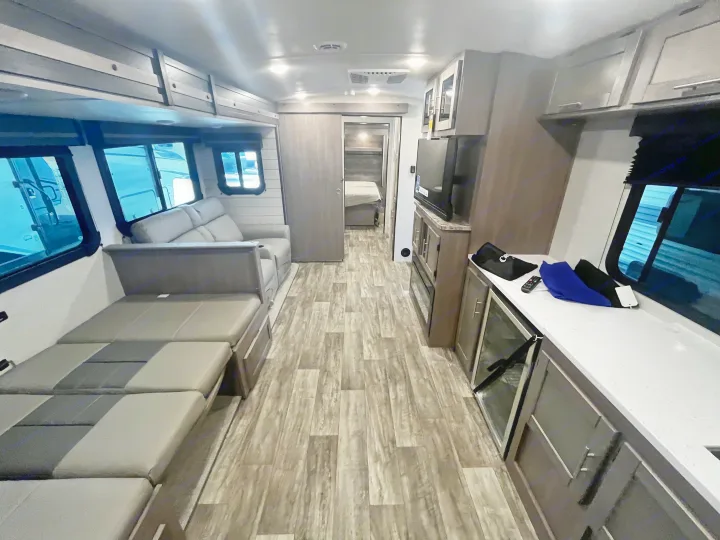 Spacious RV rental interior with modern kitchen, living space, and bedroom. Features wood-look flooring and ample storage.. Crossroads RV Sunset Trail Super Lite 2023