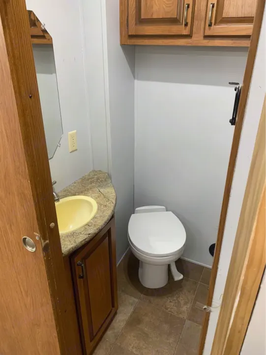 Compact RV rental bathroom: toilet, vanity with yellow sink, and mirror. Essential comfort for your travels.. Forest River Palomino Sabre 2015