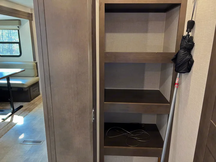 An RV rental interior features built-in storage shelves, a compact umbrella, and a dining nook with a window.. Forest River Flagstaff Super Lite 2021
