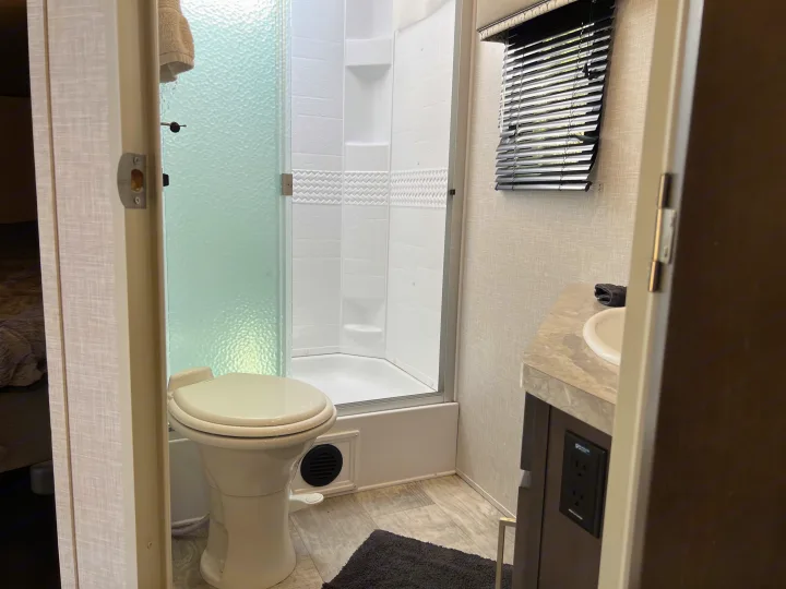 RV rental bathroom featuring a compact toilet, corner shower, and vanity sink, optimizing space for travel comfort.. Forest River Flagstaff Super Lite 2021