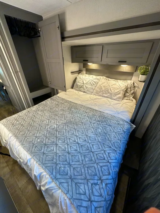 Cozy RV rental bedroom featuring a comfortable bed, overhead storage, and a wardrobe, ideal for travel comfort.. Forest River Solera 2021