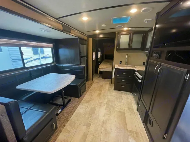 Spacious RV rental interior featuring a modern kitchen, dining booth, and partial view of a cozy bedroom area.. Grand Design Other 2018