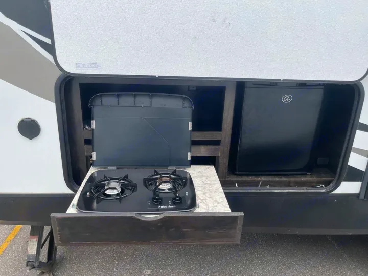 This RV rental's outdoor kitchen boasts a two-burner Suburban cooktop and mini-fridge, perfect for camping convenience.. Grand Design Other 2018