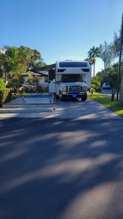 Spacious rv rental parked at a tropical campsite with an outdoor living area and a cute dog.. Jayco Greyhawk 2023