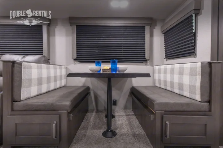 RV rental dinette featuring comfortable grey and plaid seating with a table set for dining, and window blinds.. Grand Design Transcend 2022