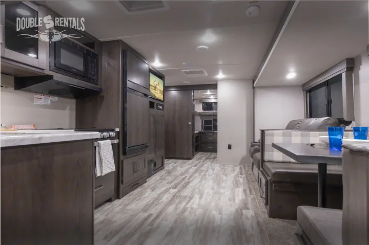 Modern rv rental interior showcasing a full kitchen, comfy dinette, and bunk beds. Ideal for a family camping trip.. Grand Design Transcend 2022