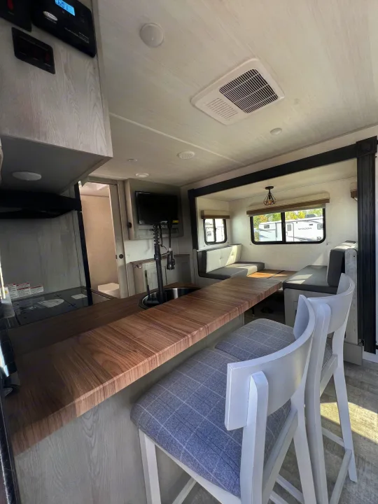 Spacious RV rental interior featuring kitchen, dining, and living areas with modern design and light wood accents.. Forest River IBEXMBS 2023
