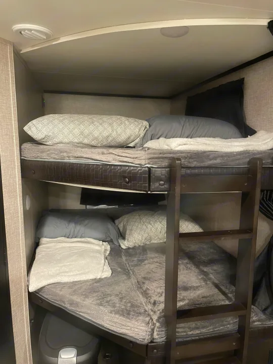 Inside this RV rental, comfortable bunk beds are made up with bedding, offering practical sleeping space for travelers.. Jayco Jay Feather 2022