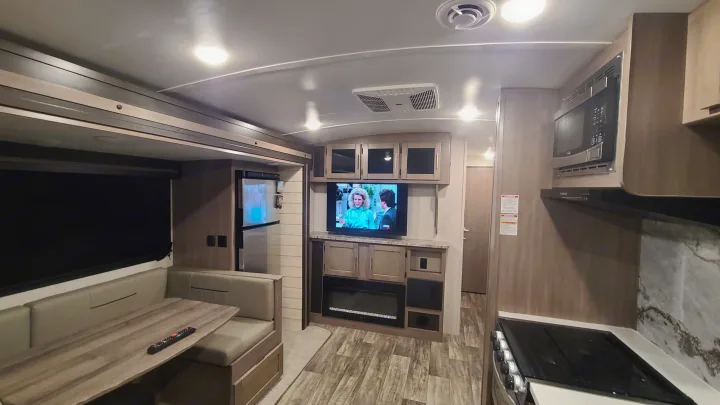 Inside a comfortable rv rental: living area with dinette, TV, fireplace, and full kitchen with microwave & stove.. Crossroads RV Sunset Trail Super Lite 2022