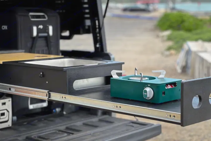 Perfect for your rv rental: a robust pull-out outdoor kitchen with sink, compact green stove, and cutting board for camping meals.. Jeep Gladiator 2022
