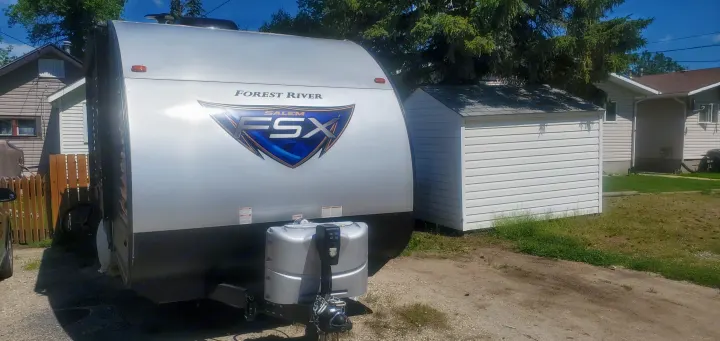 A Forest River Salem FSX travel trailer, ideal for your next rv rental, is parked outside beside a white shed.. Forest River Salem FSX 2019