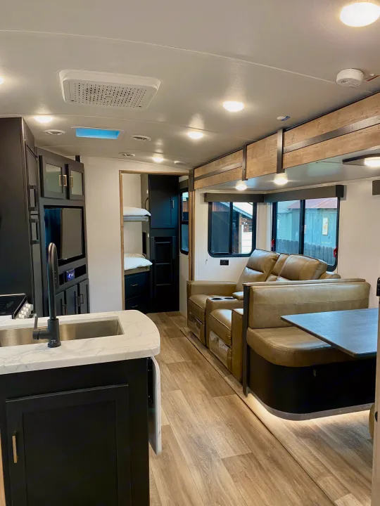 Bright, modern RV rental interior with kitchen, cozy living area (recliners, dinette), and bunk beds for travel.. Keystone RV Outback Ultra-Lite 2022
