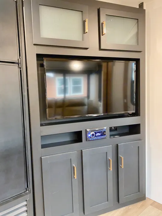 Modern RV rental interior: dark gray entertainment center with TV, stereo, and stylish cabinetry.. Keystone RV Outback Ultra-Lite 2022