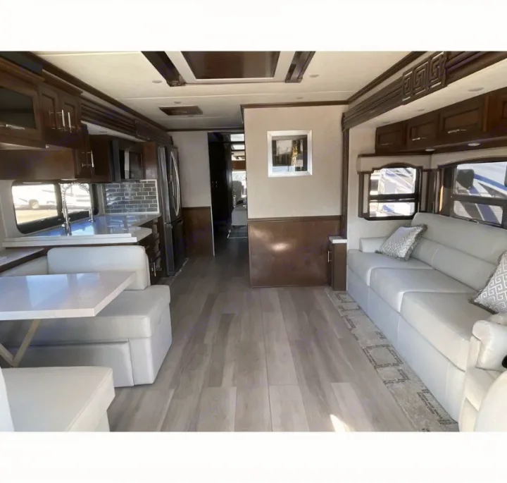 Spacious luxury RV rental interior showing a modern kitchen, comfortable dinette, and living area with sofa.. Newmar Ventana 2023
