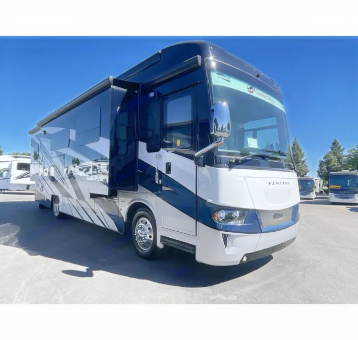 A large, luxurious white and dark blue Ventana motorhome, perfect for an rv rental vacation. Other RVs are visible.. Newmar Ventana 2023