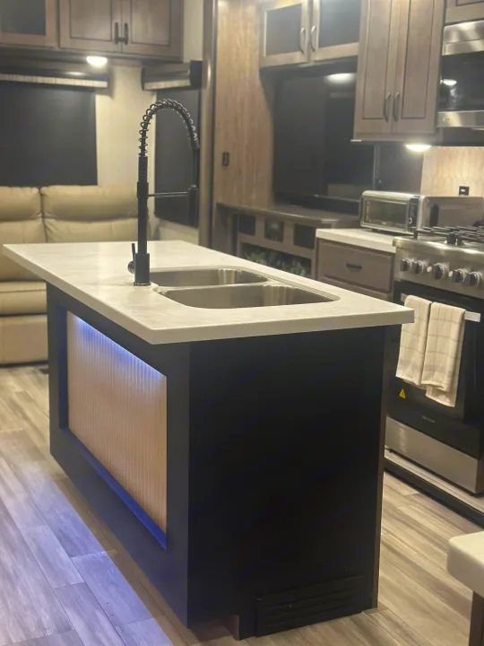 Explore this RV rental's modern kitchen island with dual sinks, sleek appliances, and cozy living space.. Cedar Creek Cedar Creek Fifth Wheel 2022