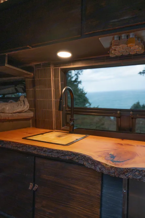 RV rental: Rustic kitchen with live-edge wood counter, modern sink, and stunning ocean view. Perfect for your next adventure!. Mercedes-Benz Sprinter 2021