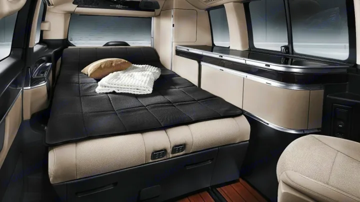 Experience an RV rental with this camper van interior, showcasing a comfortable bed, integrated kitchenette, and practical storage.. Mercedes Marco Polo Class V 2019