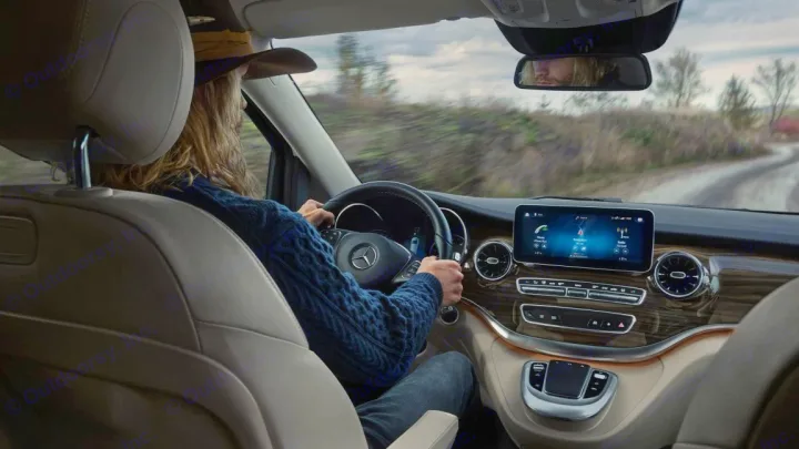 Modern RV rental interior with driver in hat, navigating a scenic road. Dashboard, steering wheel, and screen visible.. Mercedes Marco Polo Class V 2019